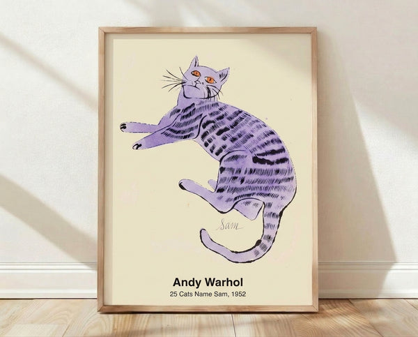 Pop art poster featuring 25 stylized cats in bold black, white, red, blue, and yellow tones, displayed as a framed print on a wall.