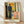 Framed expressionist self-portrait featuring a faceless figure positioned between a clock and bed, rendered in dark earthy tones with angular brushwork conveying introspection and melancholy.