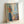 Expressionist wall art depicting a woman examining her reflection, characterized by distorted forms and a melancholic atmosphere in ochre and gray tones.