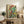 Framed modern abstract print with explosive splatter composition in bold crimson, teal green, and bright yellow against cream surface.