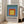 Abstract geometric composition of nested squares in muted blue, orange, and yellow hues; framed Bauhaus-style art print with meditative aesthetic.