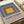 Bauhaus-inspired geometric artwork of nested squares in periwinkle blue, golden yellow, rust orange, and teal; minimalist poster with contemplative mood.