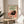Vintage-styled framed print featuring a charming black cat surrounded by a chair, coffee, and fishbowl in creams, forest greens, and warm accent colors with whimsical art nouveau elements.