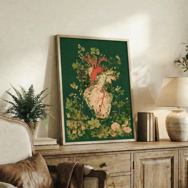 Framed poster of an anatomical heart sprouting wildflowers and vines in soft blush pink, yellow, and deep green; surreal vintage-style botanical artwork with introspective romantic energy.