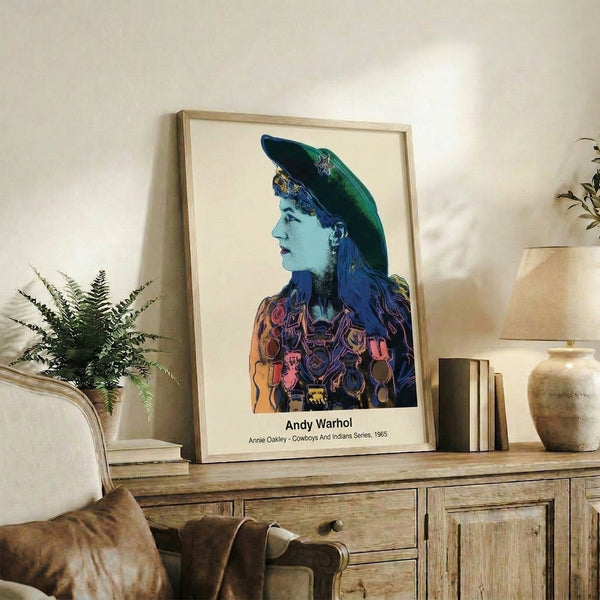 Bright and bold pop art portrait of the legendary cowgirl Annie Oakley in vibrant reds, yellows, and blues, framed as a retro art print with stark graphic appeal.