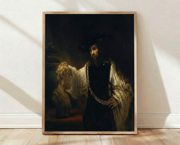 Framed Rembrandt portrait painting showing a contemplative man in rich golden robes gazing at a classical bust, rendered in warm earth tones and deep shadows.