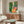 Vibrant botanical illustration of a peacock on an ornate coral armchair, surrounded by a potted plant and teacup in elegant Art Nouveau style.