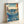 Dramatic ocean scene rendered in traditional Japanese woodblock style: powerful whirlpool in shades of prussian blue and turquoise, rocky coastline, mountain silhouettes, and flying birds creating majestic mood.