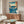 Japanese woodblock art depicting powerful whirlpool in prussian blue waves with turquoise swirls, cream foam, brown rocky shore, distant peaks, and flying birds in vintage aesthetic style.