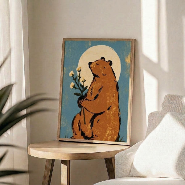 Cozy wabi sabi wall art depicting a bear clutching botanical flowers with a glowing full moon overhead, styled in soft retro colors and minimal linework.