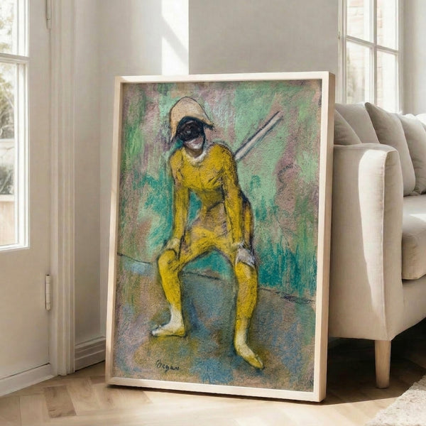 Framed reproduction of Degas' iconic ballet scene featuring a figure in striking yellow harlequin attire, with warm ochre and neutral tones throughout.