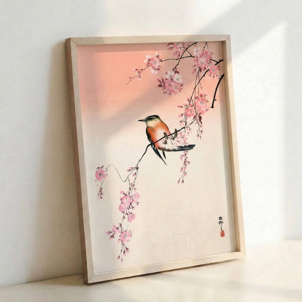 Framed poster showing a graceful bird on blooming cherry branches in muted coral orange and cream hues, inspired by traditional Japanese woodblock aesthetics.