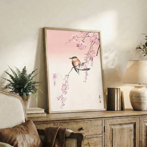 Minimalist Japanese wall art print portraying a bird amid delicate cherry blossoms in pale pink and cream, evoking serene contemplative mood.