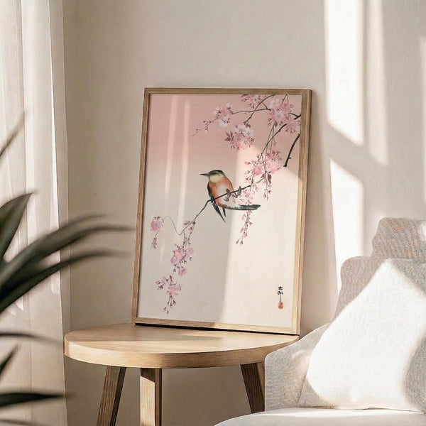 Elegant Japandi-style framed poster of a bird on spring flowering branches rendered in soft coral, pink, cream, and charcoal tones.