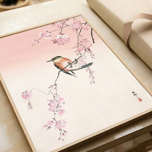 Tranquil Japanese woodblock-inspired art print of a bird perched among pale pink cherry blossoms and cream-colored branches, displayed framed on wall.