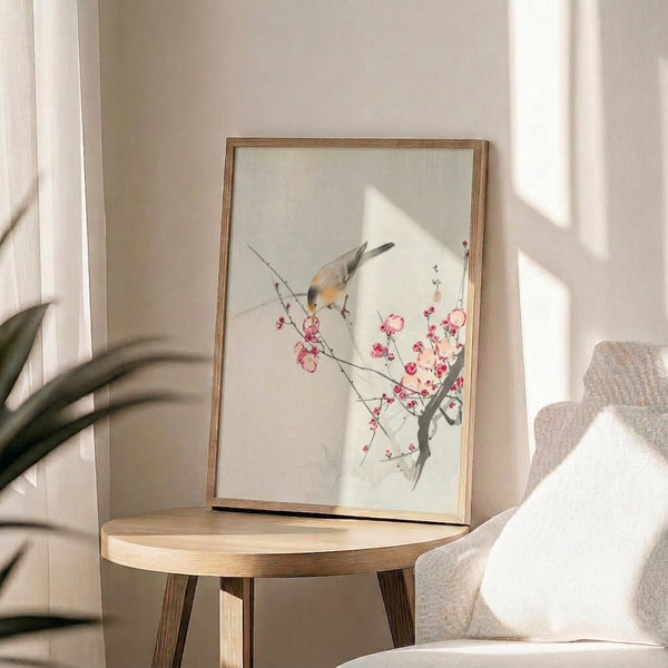 Serene framed watercolor painting blending Japanese woodblock influences with a solitary bird nestled near pale pink and orange cherry blossoms on an airy cream ground.