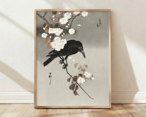 Traditional Japanese woodblock print featuring a black crow perched on a flowering branch with delicate blossoms and leaves in cream, brown, and muted tones; framed poster with serene, elegant aesthetic.