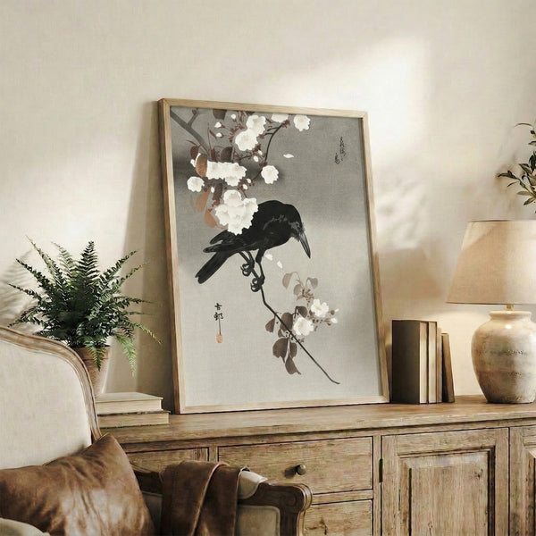 Traditional Japanese artwork featuring a black bird nestled among cream and white flowers and leaves on a branch, rendered in woodblock style with calm, elegant mood.