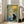 Zen-inspired wall art depicting a black cat in a peaceful garden setting with a woven lantern, bamboo stems, and blooming florals in calming cream and sage green hues.