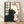 Serene line art poster of a black cat gazing out a window framed by cherry blossom branches in soft pink and cream tones, rendered in Japanese woodblock style.
