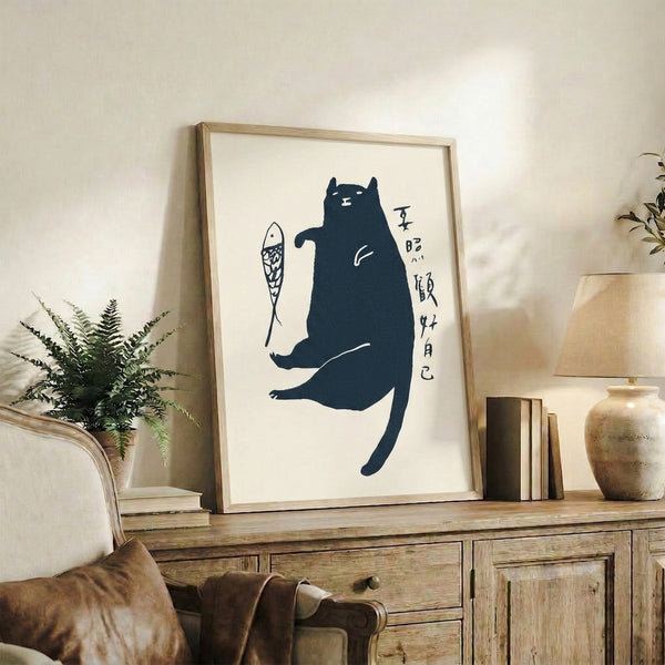Minimalist framed poster depicting a black cat entranced by a fish, using flowing navy lines and cream background in peaceful, folksy style.