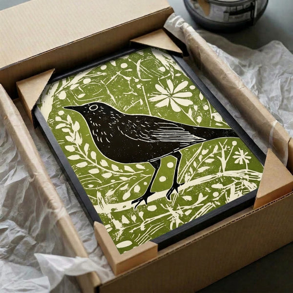 Cream-colored art print with folk-inspired blackbird illustration in black and olive green linework, capturing quiet naturalism and cottage-core botanical beauty on a wall.