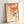 Framed Japanese woodblock poster depicting an autumn bird surrounded by ornate branches and berries in warm orange and cool blue palette.
