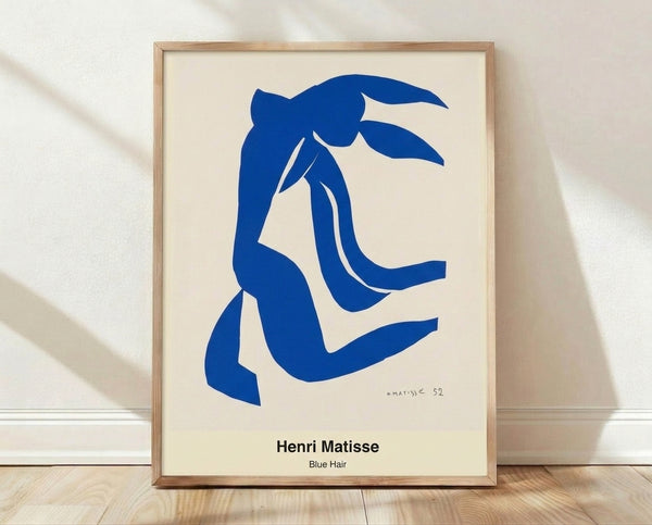 Abstract portrait of a woman with striking blue hair and ochre accents, rendered in bold minimalist style with flesh tones and white space, framed on a wall.
