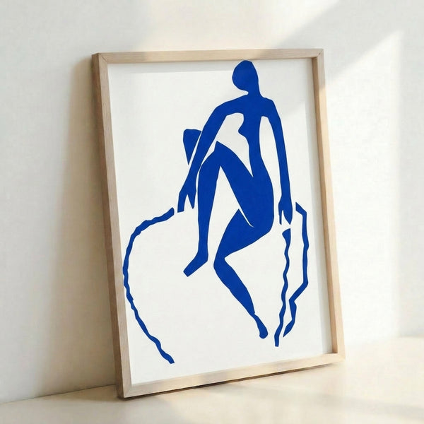 Framed contemporary wall art depicting an expressive blue form mid-leap, capturing movement through bold color field and organic contours in the modernist cutout aesthetic.