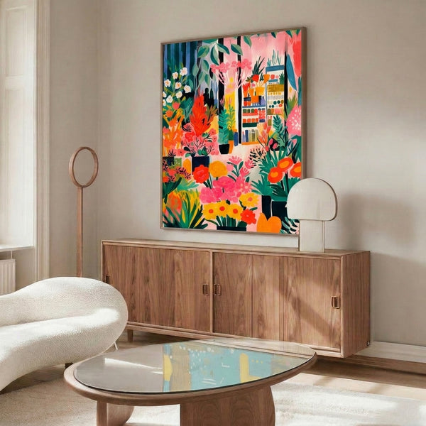 Modern botanical art print featuring a woman amid flowering plants, leafy arrangements, and decorative shelving in bold Bauhaus-influenced colors of coral, emerald, golden yellow, and cream.