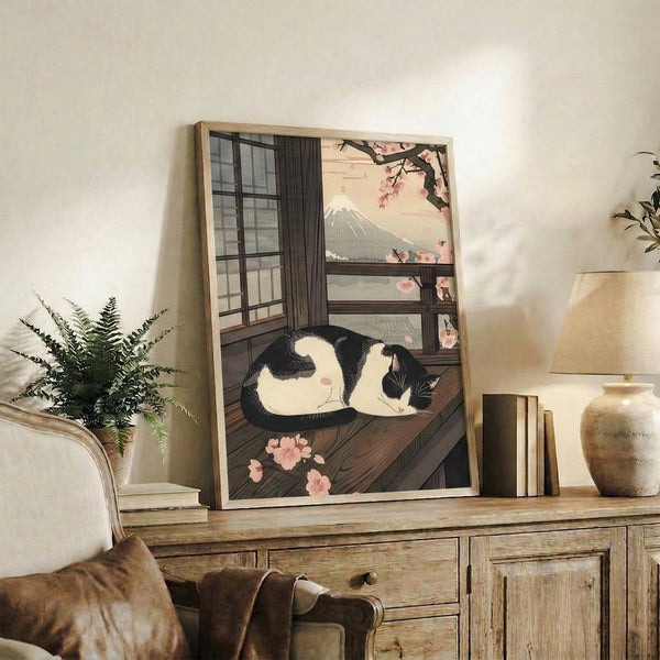 Peaceful woodblock-style poster combining traditional Japanese imagery—a tuxedo cat, cherry blossoms, and Mount Fuji—in soft cream and pink hues.