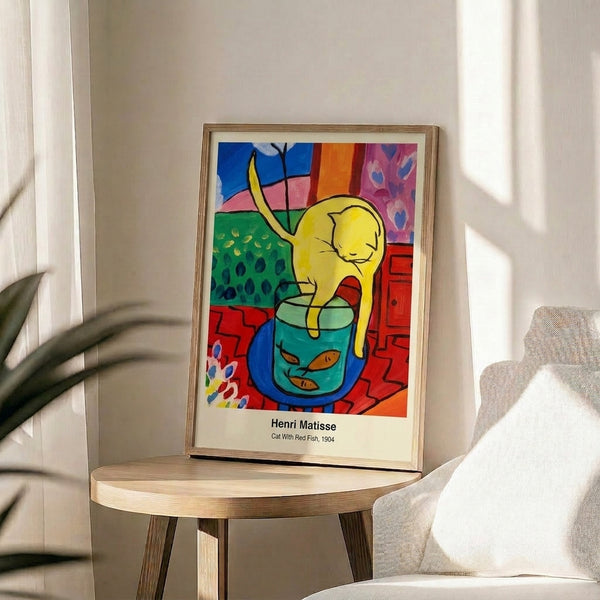 Framed print featuring an attentive cat watching a vivid red fish, painted in impressionist brushwork with vibrant complementary colors evoking intimate domestic charm.