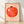 Whimsical folk art poster featuring a cheerful tomato character with a playful expression in coral red and soft pink tones, framed on a wall.