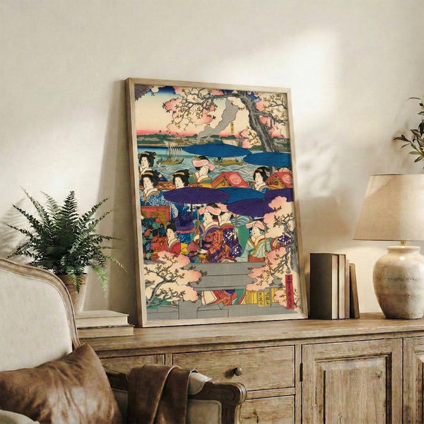 Japanese-inspired framed print showing a geisha under parasol on water amid cherry blossom trees and riverside buildings, rendered in pink, blue, cream, and metallic gold.