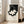 Minimalist modern poster with bold black abstract shapes on cream ground, suggesting three-dimensional form in elegant, contemplative style.