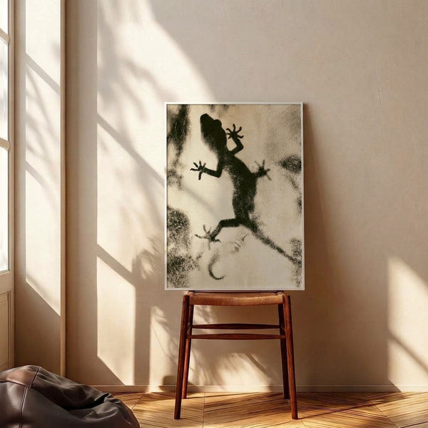 Abstract gecko silhouette rendered in loose, flowing black lines on a tan and cream surface, creating a zen-inspired artistic study.