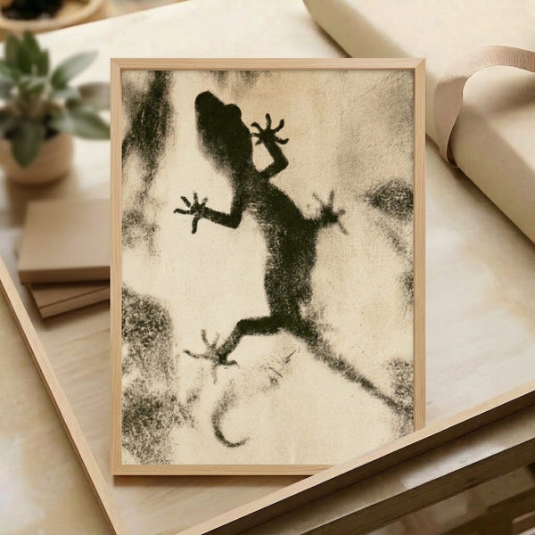 Framed wall art featuring a quirky gecko outline in charcoal and black ink, with minimalist linework evoking a contemplative, wabi sabi aesthetic.