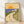 Vintage art deco coastal landscape poster with a golden sun rising over blue sea, cream-colored road, and green vegetation with distant houses in warm and cool tones.