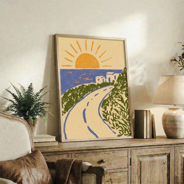 Retro-style framed print depicting a serene seaside road at sunrise, rendered in art deco design with golden orange, cobalt blue, and forest green hues.
