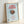 Sleek minimalist poster showcasing a coffee saucer and cup in warm brown and red hues with a peaceful light blue backdrop, perfect for contemporary living spaces.