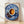 Watercolor still life poster featuring a cobalt blue coffee cup with golden orange accents, scattered coffee beans, and ceramic dishware in warm cream and brown tones, framed on a wall.