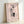 Contemporary line art wall print in black, blush pink, and cream showing intertwined human figures in a minimalist, meditative style.