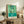 Framed abstract composition featuring boldly colored organic and geometric forms in greens and warm tones, capturing a joyful modernist aesthetic.