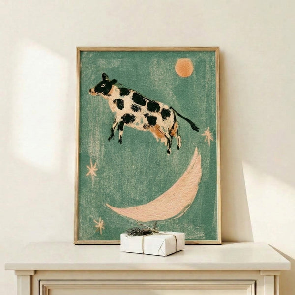 Vintage-style framed print of a playful cow jumping across the moon against a starry night sky, painted in muted sage, cream, and warm apricot hues with folk art charm.