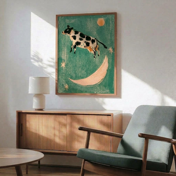 Dreamlike folk art print showing a silhouetted cow soaring above the moon with scattered stars, captured in nostalgic color palette of sage, cream, black, and warm apricot orange.