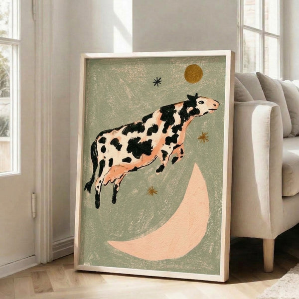 Vintage-style animal print featuring a playful cow jumping across a moon against a dreamy night sky with stars, illustrated in nostalgic folk art aesthetic with earthy and warm colors.