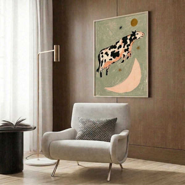 Cottagecore-inspired animal artwork showing a cow soaring over the moon in vintage folk art style, featuring a nostalgic color palette of sage green, cream, black, and golden yellow tones.
