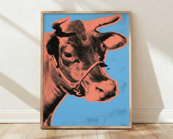 Bold pop art framed poster featuring a stylized cow head in vibrant orange against a bright blue background, modern minimalist print.