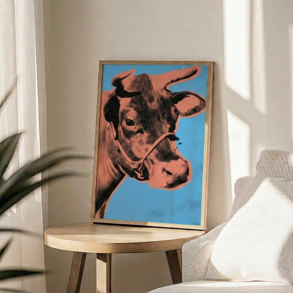 Pop art cow poster in vivid orange and blue, framed contemporary print with bold graphic design and vibrant color contrast.