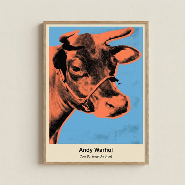 Framed modern pop art poster featuring a stylized cow portrait in orange against electric blue background with graphic white details.